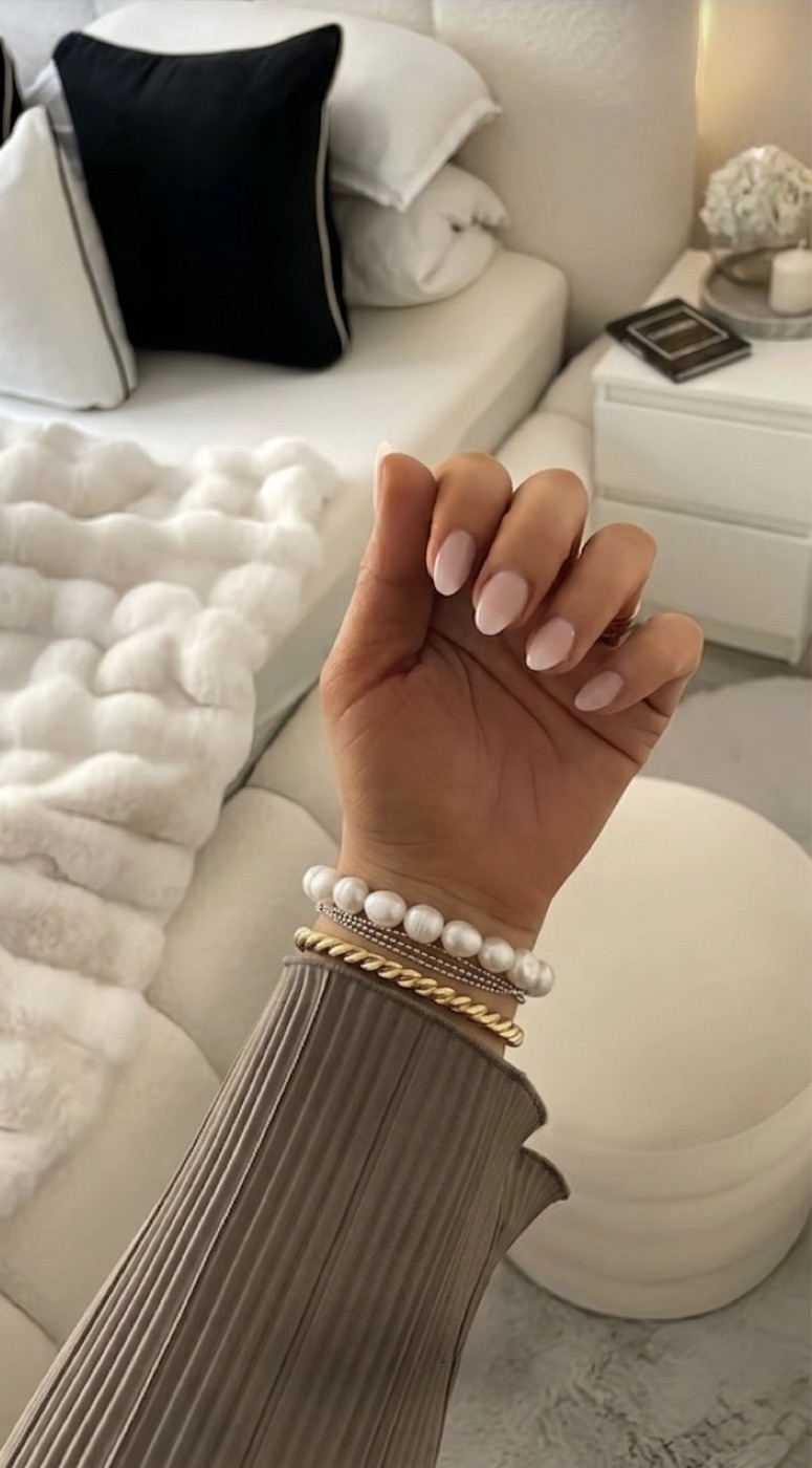 Perlen-Gold-Armband, Hand auf weißem Sofa — KI-generiert